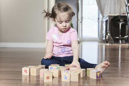 beautiful little girl playing with blocks on floor
