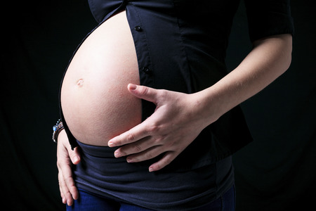 A pregnant woman caressing her belly over white 