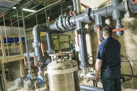 repairman engineer of fire engineering system or heating system open the valve equipment in a boiler...