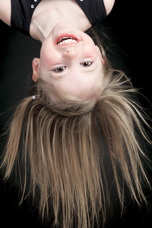 Happy little girl hanging upside down isolated on whiteの写真素材