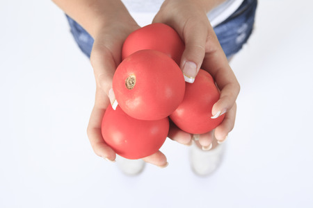 Beautiful close-up portrait of young woman with tomato. Healthy food and vegetables concept. Skin care and beauty. Vitamins and minerals.の写真素材