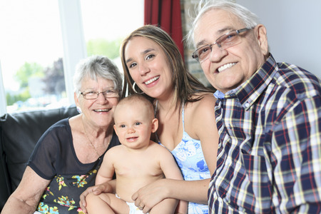 Portrait of happy mature couple with daughter and granddaughter in home