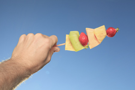 closeup of fruit in men hand over blue skyの写真素材