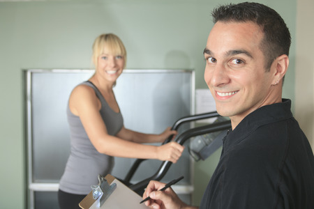 gym woman personal trainer man with weight training equipmentの写真素材
