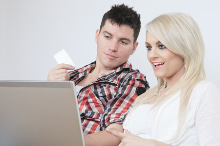 A Couple on sofa with laptop who want to buy something on the Internet.の写真素材