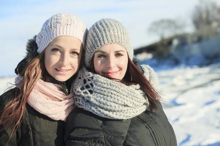Two happy young girls having fun in winter parkの写真素材