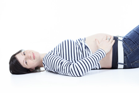 A Beautiful young pregnant woman laying studio white backgroundの写真素材