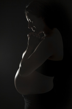 A belly of a pregnant woman on the black backgroundの写真素材