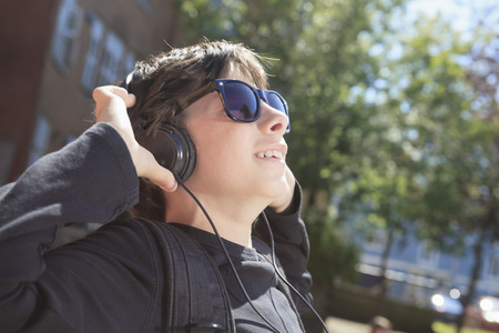 A teen boy listening to music with sun glassesの写真素材