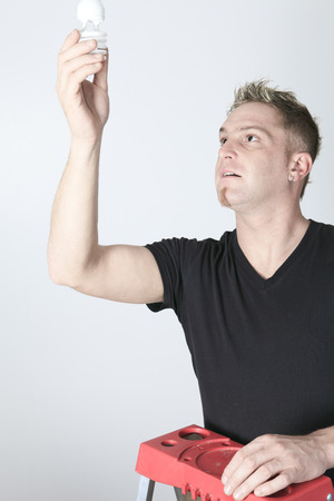 A man changing bulb in studio gray background.の写真素材