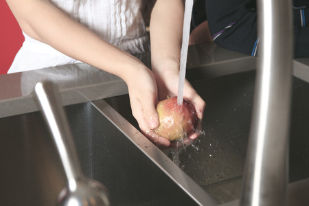 Portrait of smiling teenager girl with apple in kitchenの写真素材