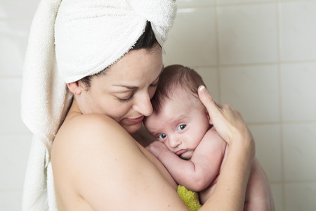 Young mother and toddler snuggling after bathtime.の写真素材