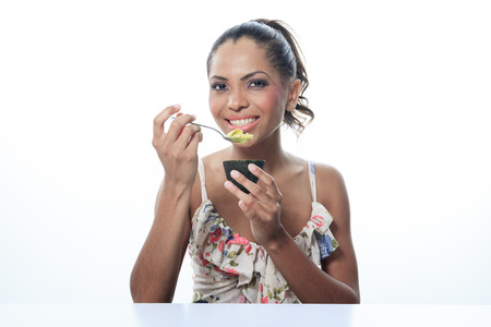 portrait of mulatto smiling woman isolated on white studio shot eating avocadoの写真素材