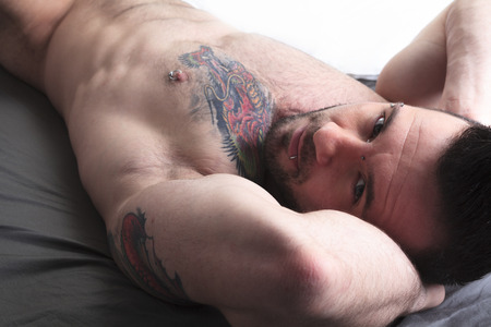A sexy naked man lay in the bedの写真素材