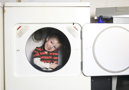 A kid on the dryer having funの写真素材