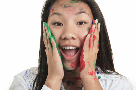 A little asian girl having fun with paint on it isolate on whiteの写真素材