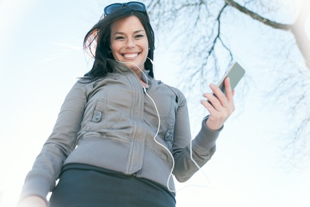 A young beauty posing over an urban city with earphone and phone