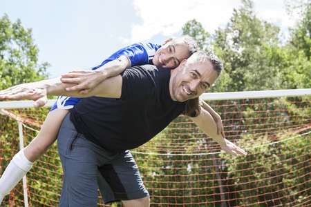 A teenager girl with his father play soccer in a beautiful dayの写真素材