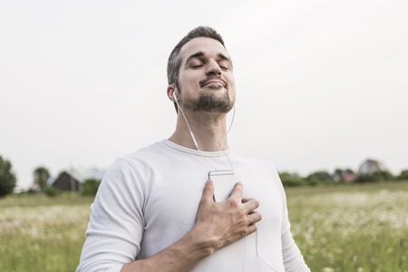 A Happy young man in a field with his cellphone