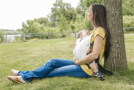 A Happy woman and child leaning on tree in city park