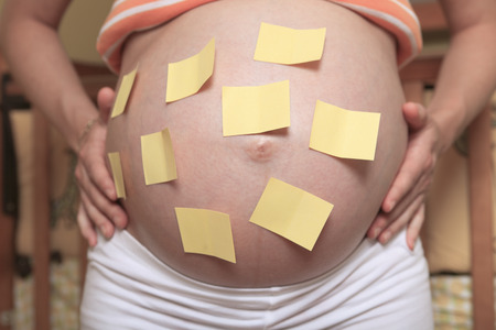 A pregnant belly and sticker notes on the baby room