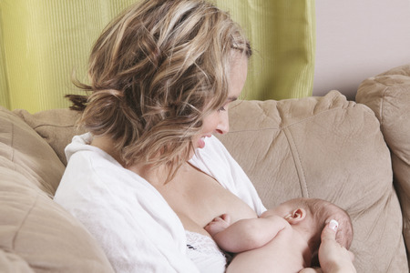 A mother feeding his baby on the sofa