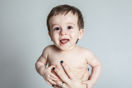 A baby cries on the hand of his motherの写真素材