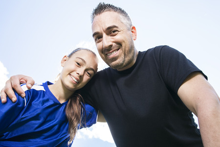 A teenager girl with his father play soccer in a beautiful dayの写真素材