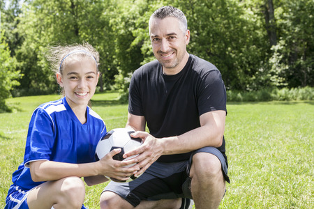 A teenager girl with his father play soccer in a beautiful dayの写真素材