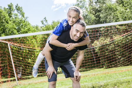 A teenager girl with his father play soccer in a beautiful dayの写真素材