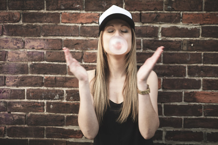 A Beautiful modern girl near the brickwall with gumの写真素材