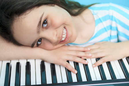 A Young girl play digital piano in the living roomの写真素材