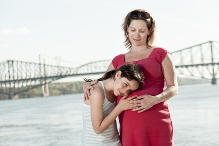 A pregnant mother and her daughter outsideの写真素材