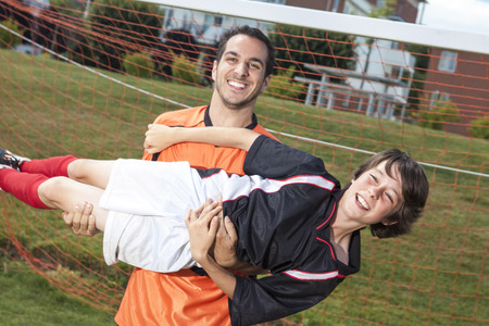 A soccer father and son posing close to the goal and a ball.の写真素材