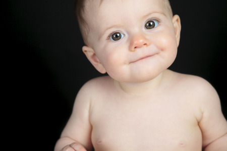Sweet little boy sitting on studio black backgroundの写真素材