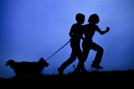 A silhouette of two happy little children.の写真素材