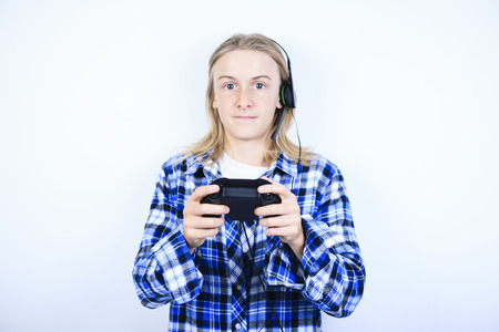 A teen boy playing video games against gray backgroundの写真素材