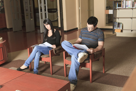 A 20 years old couple student studying at the library chairの写真素材