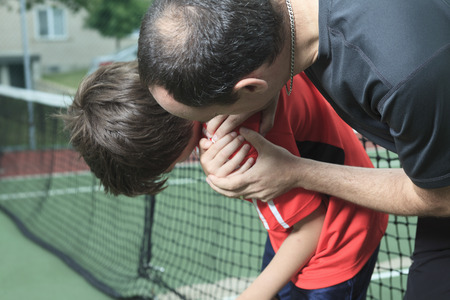 A boy tennis boy tennis player who having a injury. Father help his boy.の写真素材