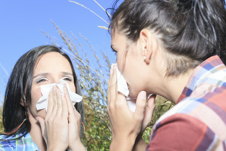 A Young woman sneezing in a field. Concept: seasonal allergy.の写真素材