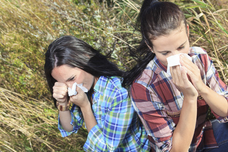 A Young woman sneezing in a field. Concept: seasonal allergy.の写真素材