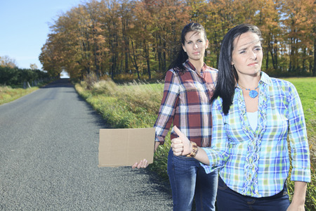 Two Womans asking for a hitch hicking on the roadの写真素材