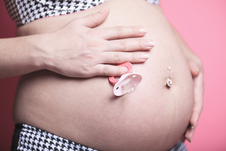 A Portrait of happy pregnant woman isolated over pink backgroundの写真素材