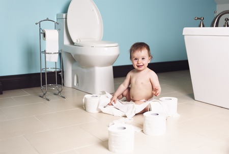 A Toddler ripping up with toilet paper in bathroomの写真素材