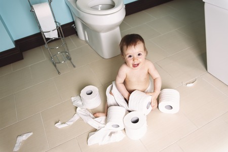 A Toddler ripping up with toilet paper in bathroomの写真素材