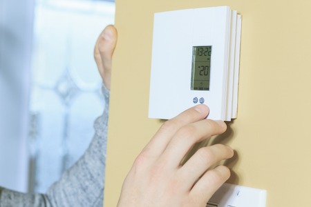 A man set the thermostat at house.