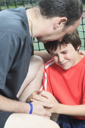 A boy tennis boy tennis player who having a injury. Father help his boy.の写真素材