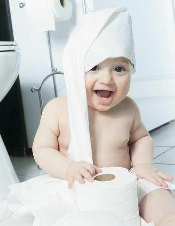 A Toddler ripping up toilet paper in bathroomの写真素材