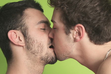 A gay couple on the bed giving kiss.の写真素材