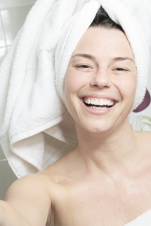 A happy woman with towel on his head on bathroom.の写真素材
